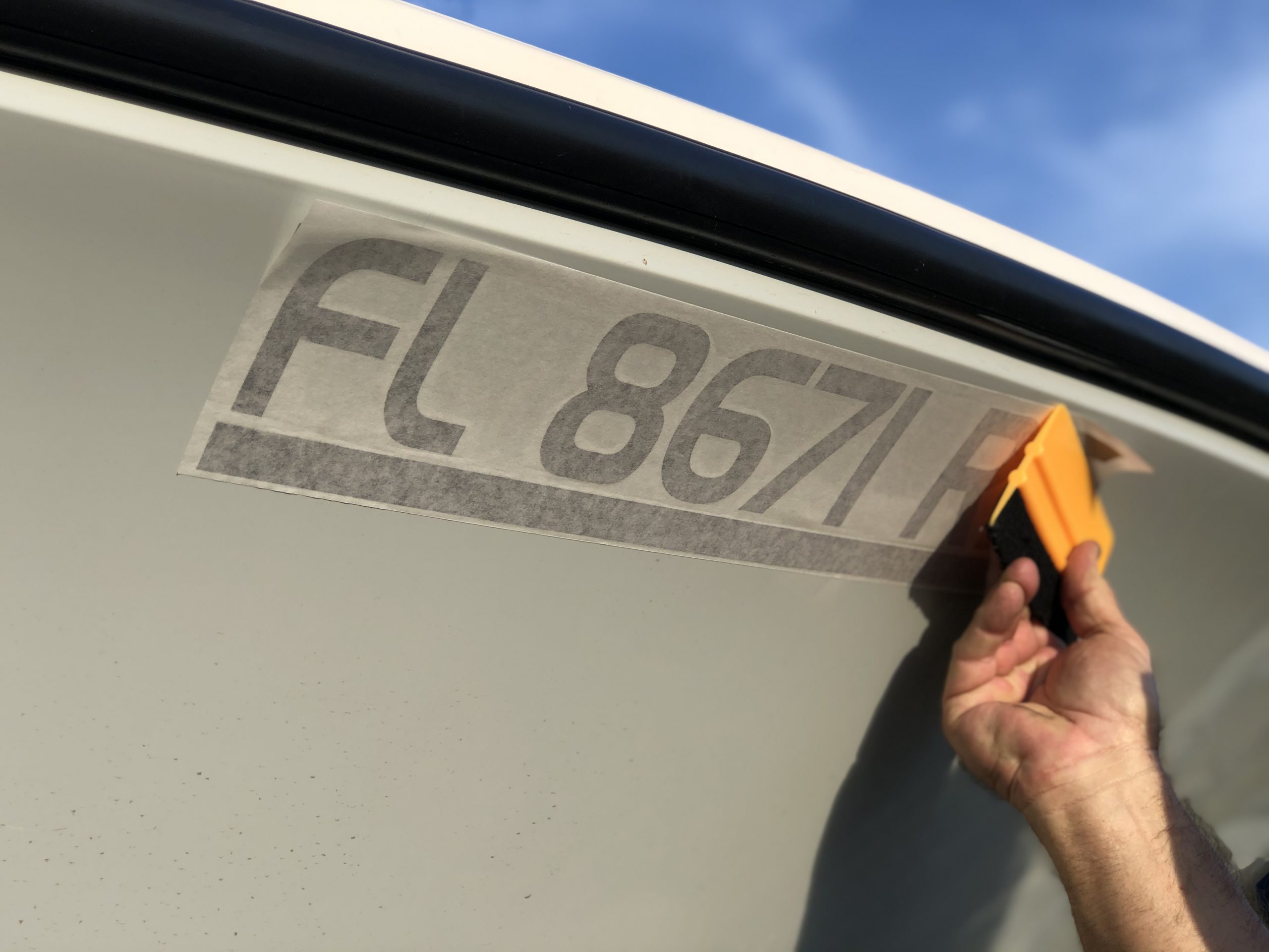 MarineReg squeegee affixing vessel registration numbers on boat